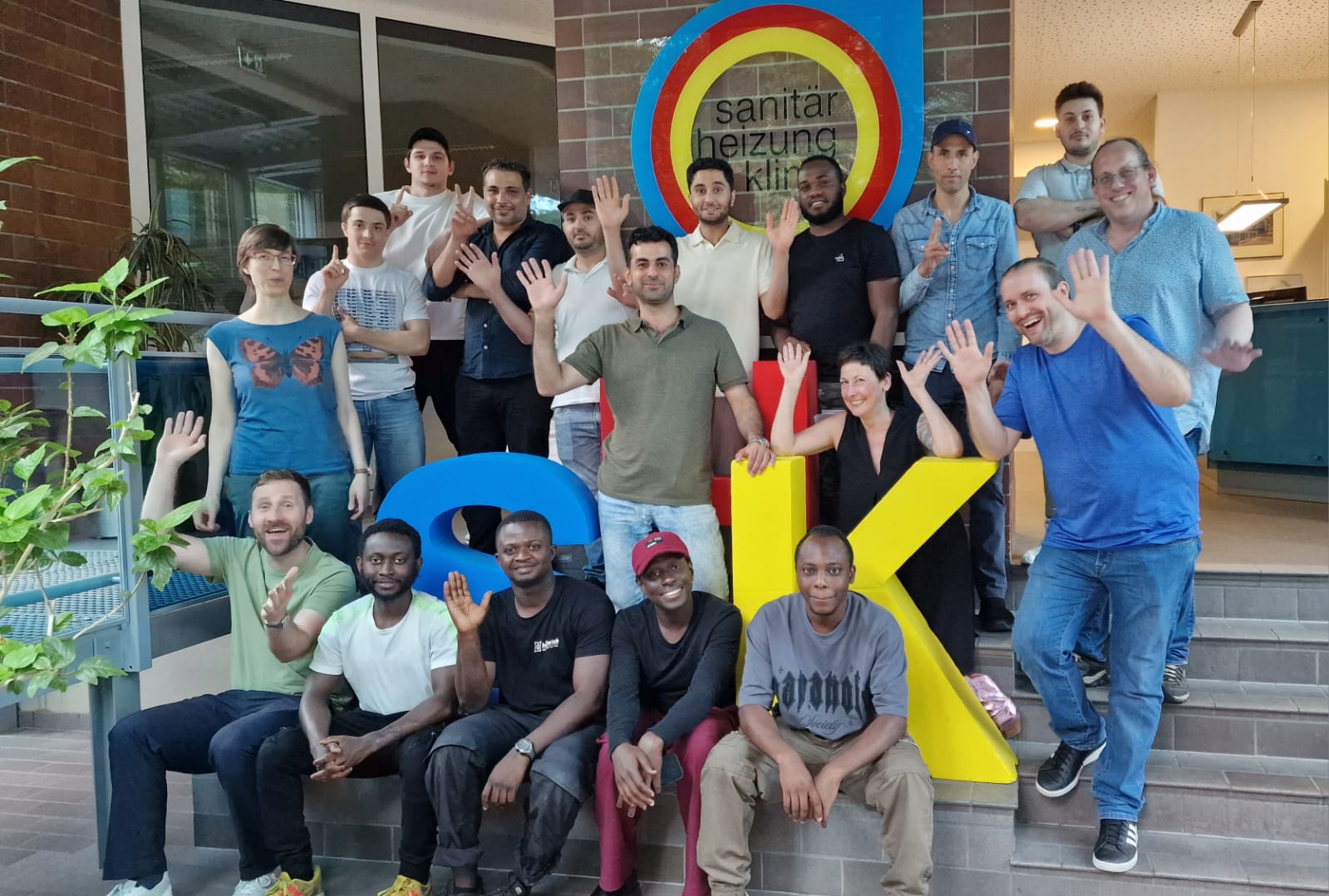 SHK Eine Gruppe von 18 Personen – Teilnehmende des Projekts sowie das Coaching- und Beratungsteam – steht lächelnd vor der Kamera. Im Hintergrund ist das Logo der Innung SHK Berlin zu sehen