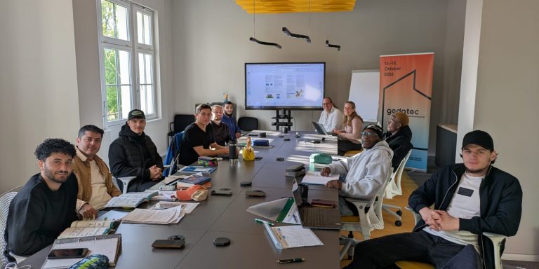 Teilnehmende des Programms SHK Kompass sitzen gemeinsam bei einem Treffen des Programms an einem Tisch.