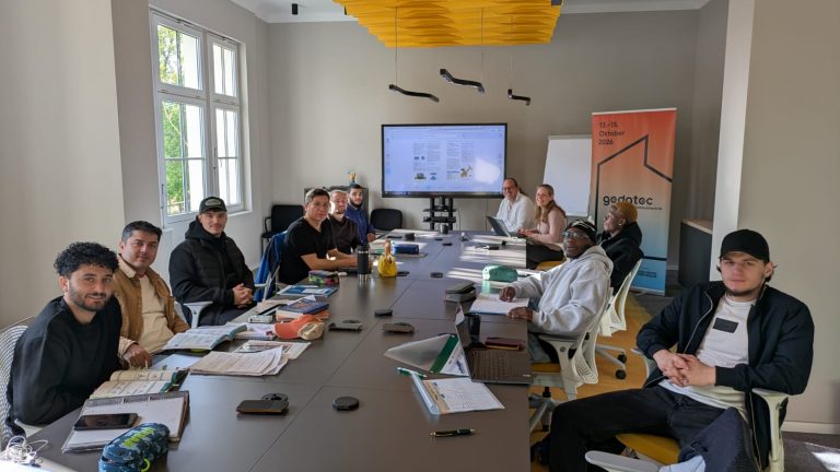 Teilnehmende des Programms SHK Kompass sitzen gemeinsam bei einem Treffen des Programms an einem Tisch.