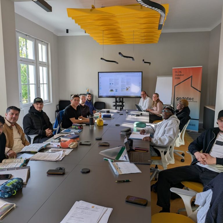 Teilnehmende des Programms SHK Kompass sitzen gemeinsam bei einem Treffen des Programms an einem Tisch.