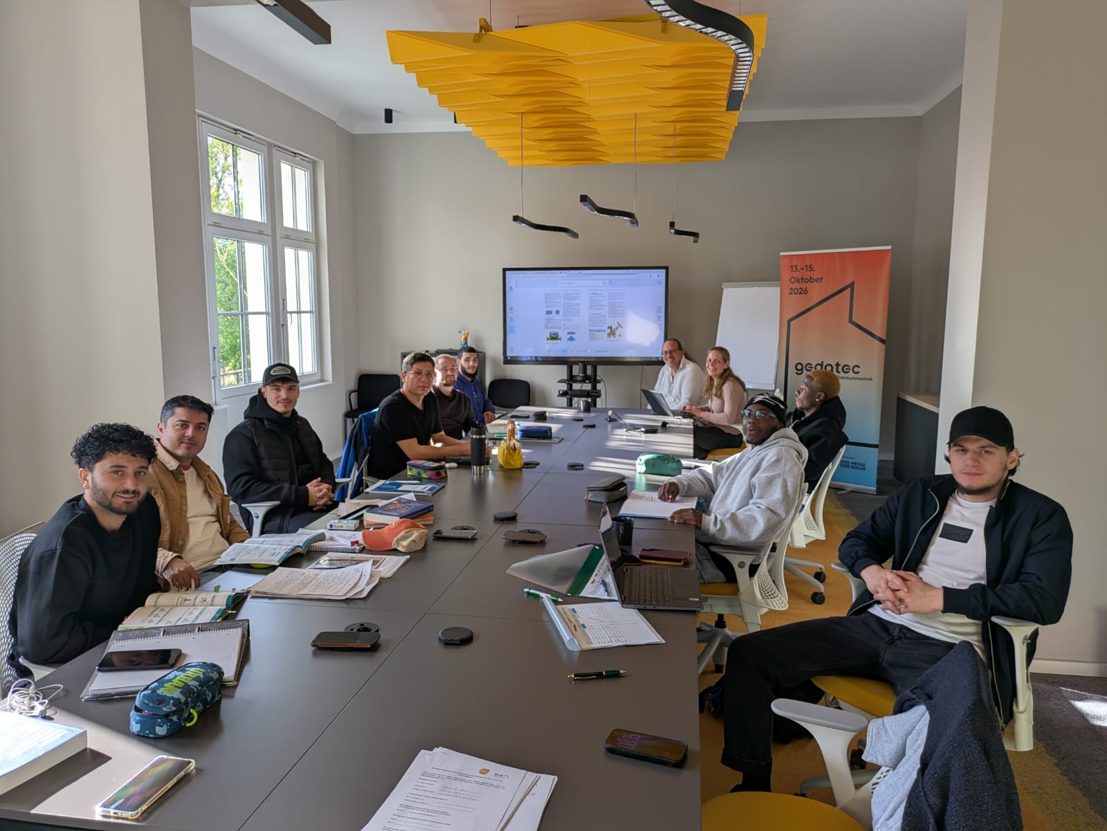 Teilnehmende des Programms SHK Kompass sitzen gemeinsam bei einem Treffen des Programms an einem Tisch.