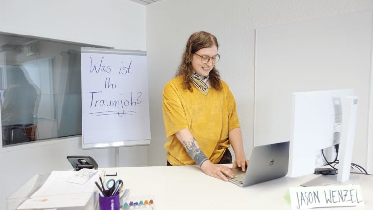 Jason Wenzel, Deutschlehrkraft im Projekt ARRIVO BERLIN Recht, Wirtschaft & Verwaltung, steht in einem Klassenraum.