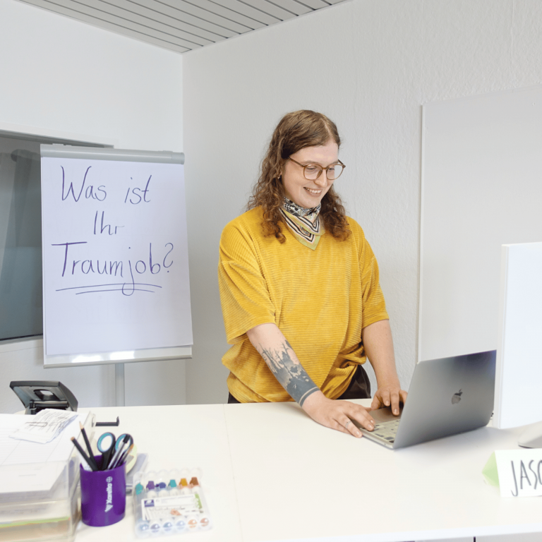 Jason Wenzel, Deutschlehrkraft im Projekt ARRIVO BERLIN Recht, Wirtschaft & Verwaltung, steht in einem Klassenraum.