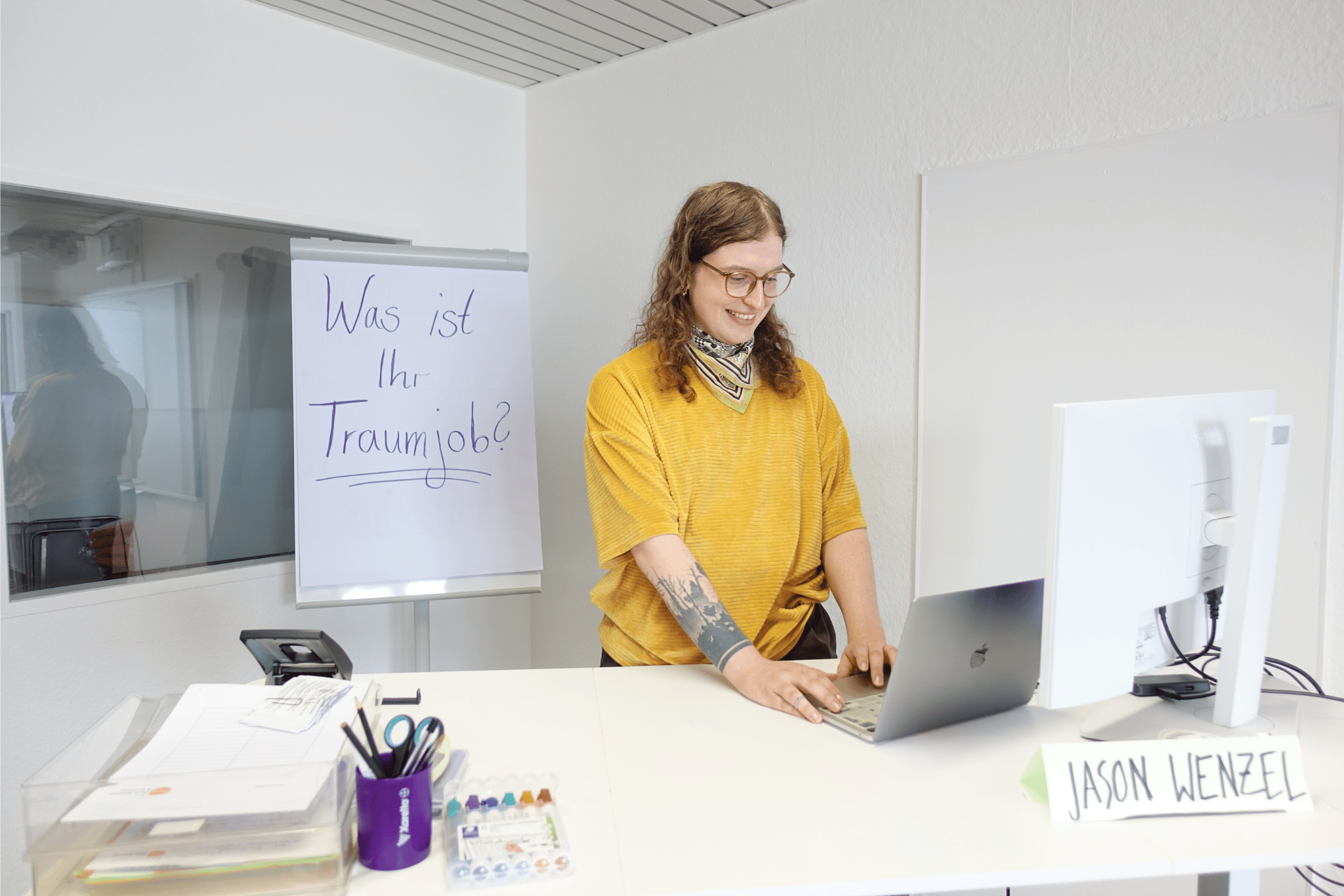 Jason Wenzel, Deutschlehrkraft im Projekt ARRIVO BERLIN Recht, Wirtschaft & Verwaltung, steht in einem Klassenraum.