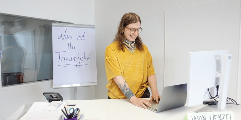 Jason Wenzel, Deutschlehrkraft im Projekt ARRIVO BERLIN Recht, Wirtschaft & Verwaltung, steht in einem Klassenraum.